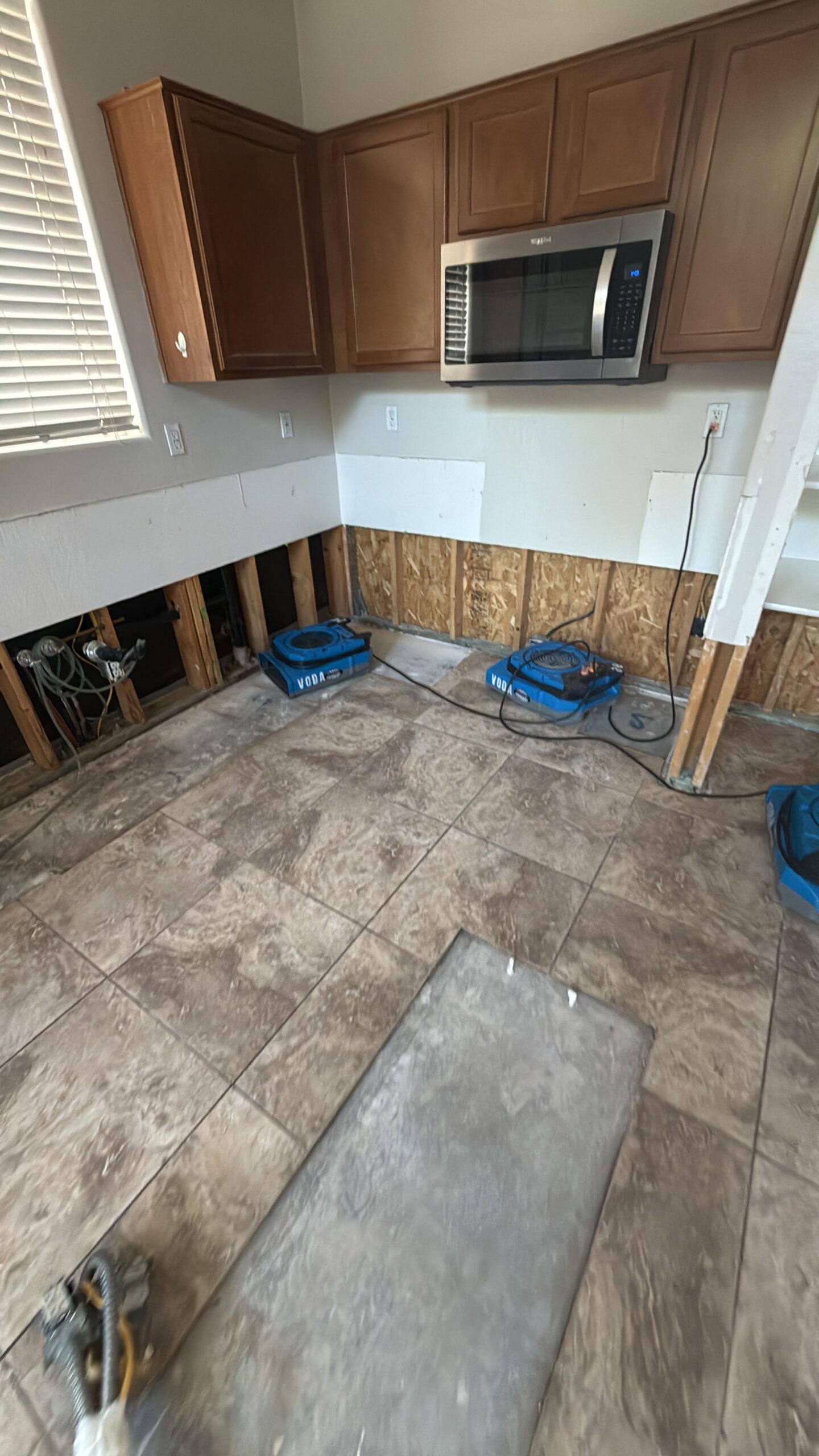 Kitchen during water damage restoration with cabinets and countertops removed