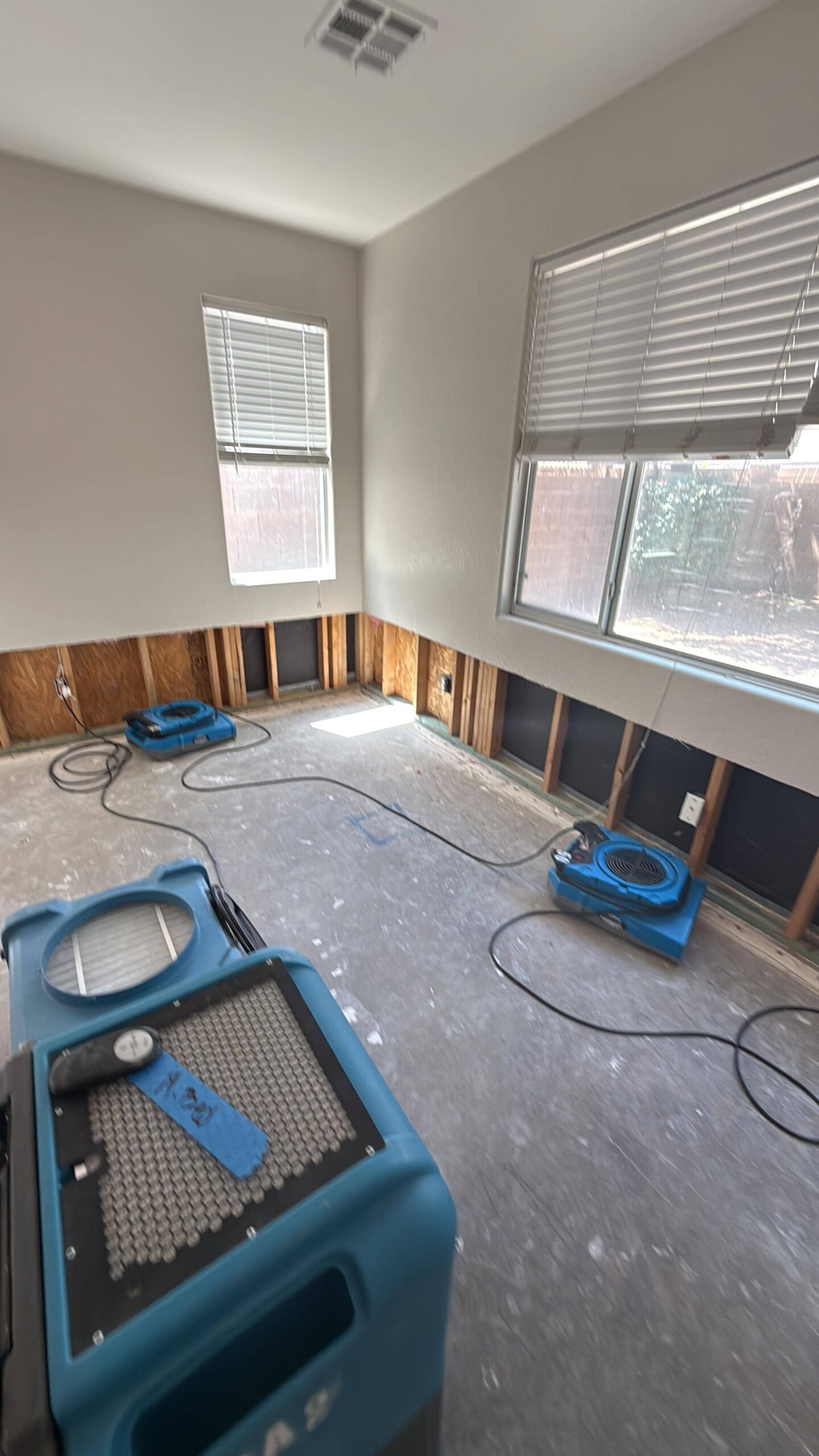 Dehumidifiers and air movers positioned for structural drying in restored room