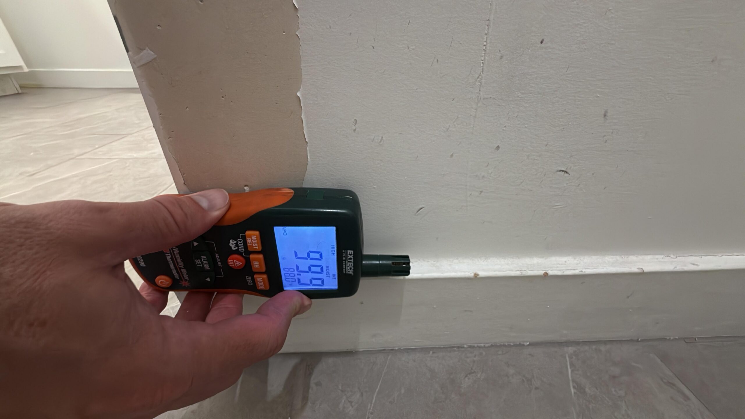 Technician taking moisture readings on drywall during water damage assessment