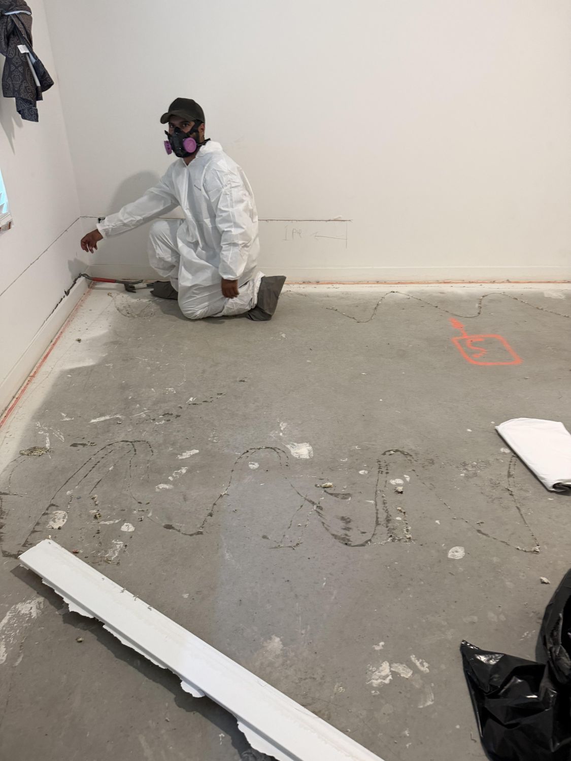 Technician in PPE performing selective drywall demolition in water damaged room